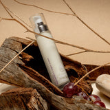 pinotage therapy regenerative night cream 30 ml bottle laying on a small tree stump with twigs and grapes surrounding it