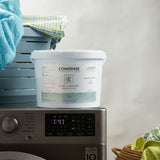 Tub containing Linen Drawer's Condense Specialised Washing Powder 5 Kg standing on a washing machine. Sold by SR Amenities Hotel & Spa Supplies.