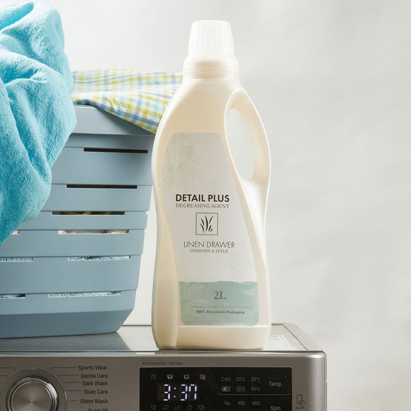 Linen Drawer's Detail Plus Degreasing Agent in a 2L container standing on a washing machine. Sold by SR Amenities Hotel & Spa Supplies.