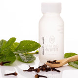 mouth wash bottle, 50ml with mint leaves and herbs surrounding it