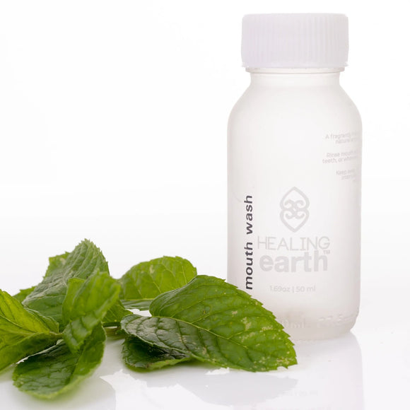 healing earth herbal mouth wash 50ml bottle with a mint leaf laying infront of it